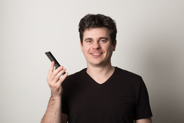 Man is talking on a cell phone. Smiling young man in a black T-shirt talking on the phone.