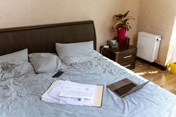 view of laptop with documents on bed. home work concept