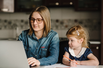 Stay at home mom working remotely on laptop computer while taking care of baby. Businesswoman,...