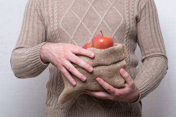 Man holds a cloth bag with apples. Bag of burlap with village apples in the hands of a man.