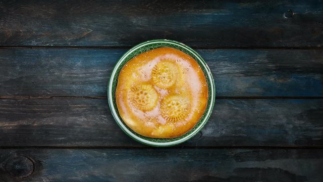 Traditional tandyr bread rotates on a plate on a wooden background. Top view