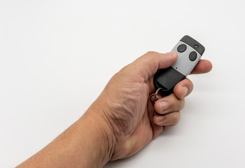 Hand holding house gate remote control in black and grey color isolated on white