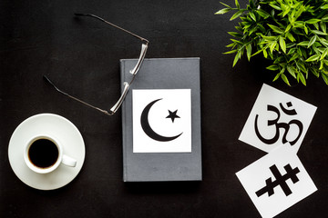 Interfaith dialogue concept. World religions symbols near book on black background top view