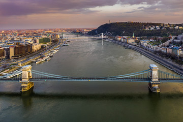 Budapest, Hungary - Aerial view of totally empty Szechenyi Chain Bridge at sunset with Elisabeth Bridge, Citadel and colorful sky at background. No traffic on the bridge due to Coronavirus outbreak