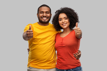 Obraz premium relationships and people concept - happy african american couple showing thumbs up over grey background