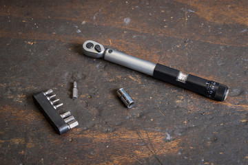 A small torque wrench with come bit tools on a brown wooden surface. Small torque wrench for tightening delicate screws.