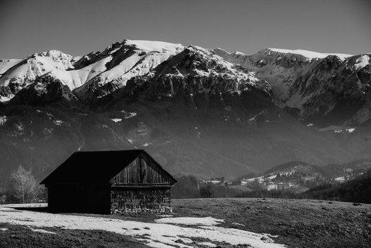 black and white image of a log cabin on a snowy mountain