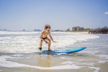 Obraz premium Healthy young boy learning to surf in the sea or ocean