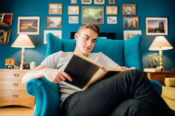 Man enjoying reading an interesting book,home alone in quarantine.Mental health self care,relaxing home activity.Studying,learning,education.Reducing stress.Self-isolation reading list.Reality escape