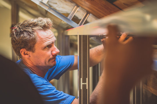 Drywall Plaster Stud Crimpers In Action. A Person Holding And Using Stud Crimping Tool In Hand While Building A Metal Drywall Construction In A House During Renovation.