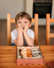 In the kitchen, a boy sits in front of a box of dried fruits, consisting of apples, peaches,...