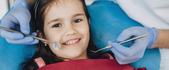 Close up portrait of a caucasian girl having an examination at the pediatric dentist while smiling at camera