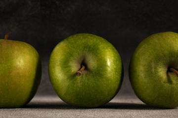 Three green juicy Apple on a background of a concrete wall