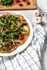 Vegan pizza with vegetables and arugula.