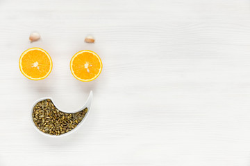 Happy face of fruit and seeds. The smiling face is made from oranges and pumpkin seeds, eyebrows of garlic. Background of useful and natural antiviral products that increase health and immunity.