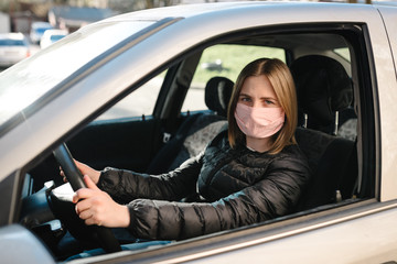 Woman wearing in the medical protective mask protect from bacteria Corona virus while driving a car. Coronavirus, disease, infection, quarantine, covid-19.