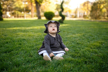 Little girl sitting on green grass