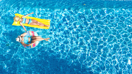 Children in swimming pool aerial drone view fom above, happy kids swim on inflatable ring donut and...