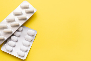 Packing blisters with pills on a yellow background with a copy space