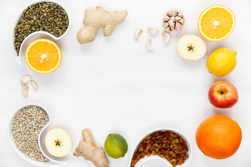 Orange, ginger, garlic, lime, apple, lemon, raisins, sunflower seeds, pumpkin seeds are spread out white background, space for text. Fighting viruses and colds with natural immune organic products