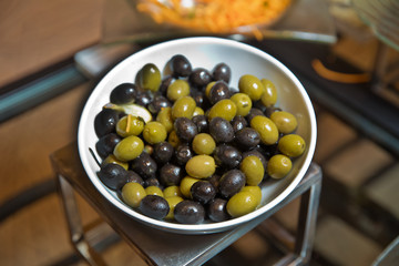Top view with space for text . Green and black olives in a white ceramic bowl .