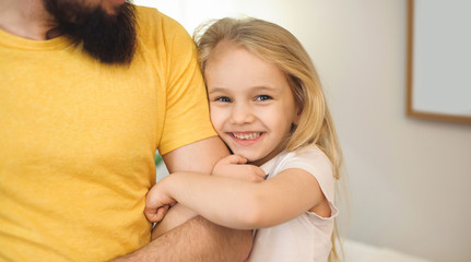 Obraz na płótnie Canvas Blonde caucasian girl embracing father hand while he is looking at her and smile