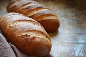 Fresh loaf on a brown background.  Traditional wheat freshly rustic baked bread, loaf of bread.