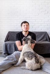 Young funny man enjoying time with his bichon frise dog