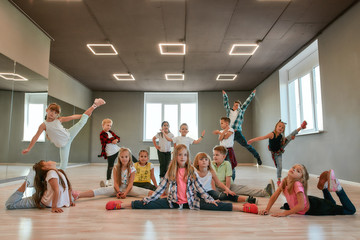 Continuez à danser. Groupe de petits garçons et filles heureux dans des vêtements à la mode posant ensemble dans le studio de danse. Équipe de danse.