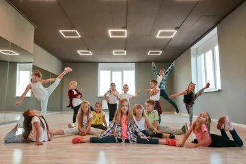 Gordijnen Blijf dansen. Groep gelukkige kleine jongens en meisjes in modieuze kleding poseren samen in de dansstudio. Dansteam. © Svitlana