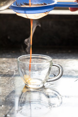 steamy masala tea being poured into a transparent glass cup