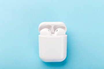 Modern wireless bluetooth headphones with charging case on a blue background.