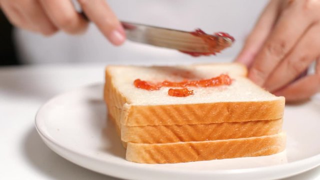 Spread strawberry jam on a slice of bread.