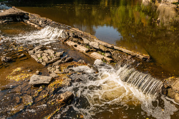 water flowing over old broken weir on a river