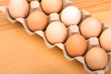 brown chicken eggs in an open cardboard box with eggs on a wooden table. Natural healthy food.