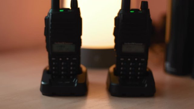 Two turn on working walkie-talkie stand on the table. Dolly movement close-up shot