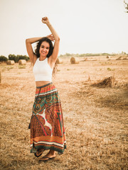 brunette beautiful woman dancing on the field with hay bales in the background