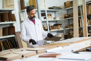 Handsome mature engineer in the laboratory examines ceramic tiles