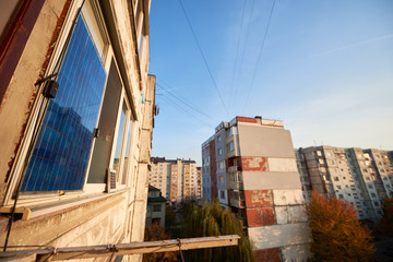 Solar panel on the balcony of multi-storey building against background of residential area of the city with clear blue sky on a warm day.