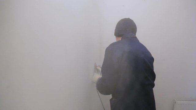 Worker removing surface cover from the wall