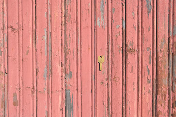 Old pink cracked wall with a yellow old key. Wooden wall with peeling paint. Background for an inscription.