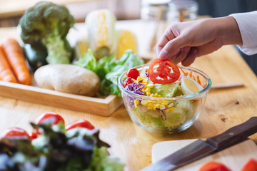 Closeup image of a female chef cooking a fresh mixed vegetables salad in kitchen