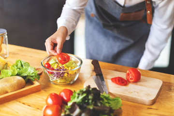 Closeup image of a female chef cooking a fresh mixed vegetables salad in kitchen