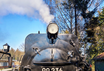 Old steam locomotive from the front with steam.