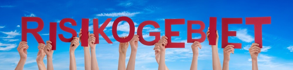 People Hands Holding Colorful German Word Risikogebiet Means Region At Risk. Blue Sky As Background