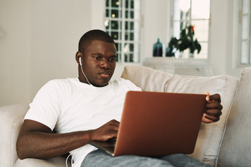 man of african appearance at home in front of a laptop