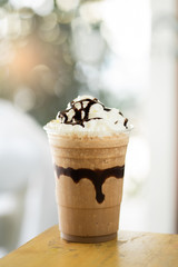 Frappe coffee placed on a wooden table in a cafe.