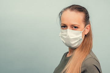 A girl is putting on a protective mask. Respiratory protection from coronavirus. Personal protective equipment for a pandemic of a viral infection. Covid-19.