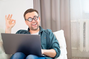 man freak with glasses working online on couch. 