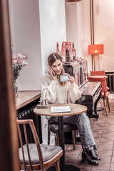 Gorgeous young woman sitting at cafe drinking coffee